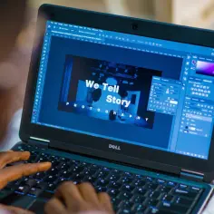 Osoba pracuje na laptopie Dell, edytując zdjęcie w programie Photoshop. Na ekranie widoczny napis "We Tell Story PHOTOGRAPHY".