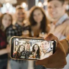 Grupa przyjaciół robi sobie zdjęcie w barze. Chcesz wiedzieć, jak zrobić idealne selfie? Oto przykład!