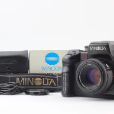 Czarna lustrzanka Minolta α-9 z obiektywem 50mm, futerałem, paskiem i pudełkiem.