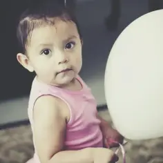 Urocza dziewczynka w różowej bluzeczce podczas sesji zdjęciowej na roczek, trzymająca biały balon.