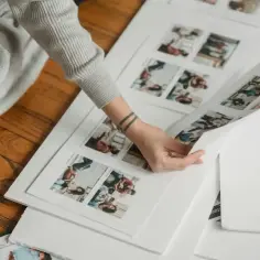 Przykłady fotoksiążki na 18 urodziny: osoba przegląda wydrukowane zdjęcia, planując układ albumu.