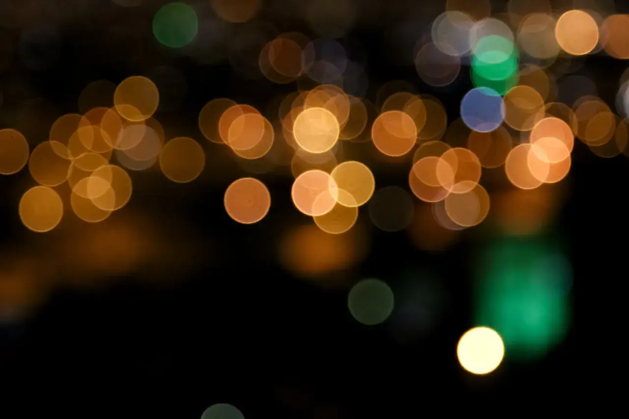Rozmyte, okrągłe światła tworzą magiczny efekt bokeh na ciemnym tle.